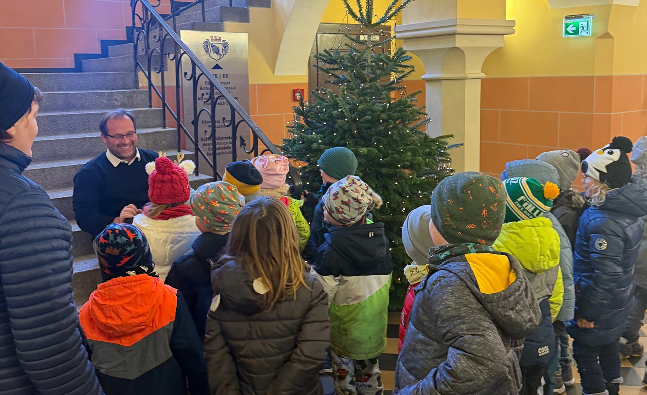 Kinder schmücken gemeinsam mit dem Bürgermeister den Weihnachtsbaum im Rathausfoyer